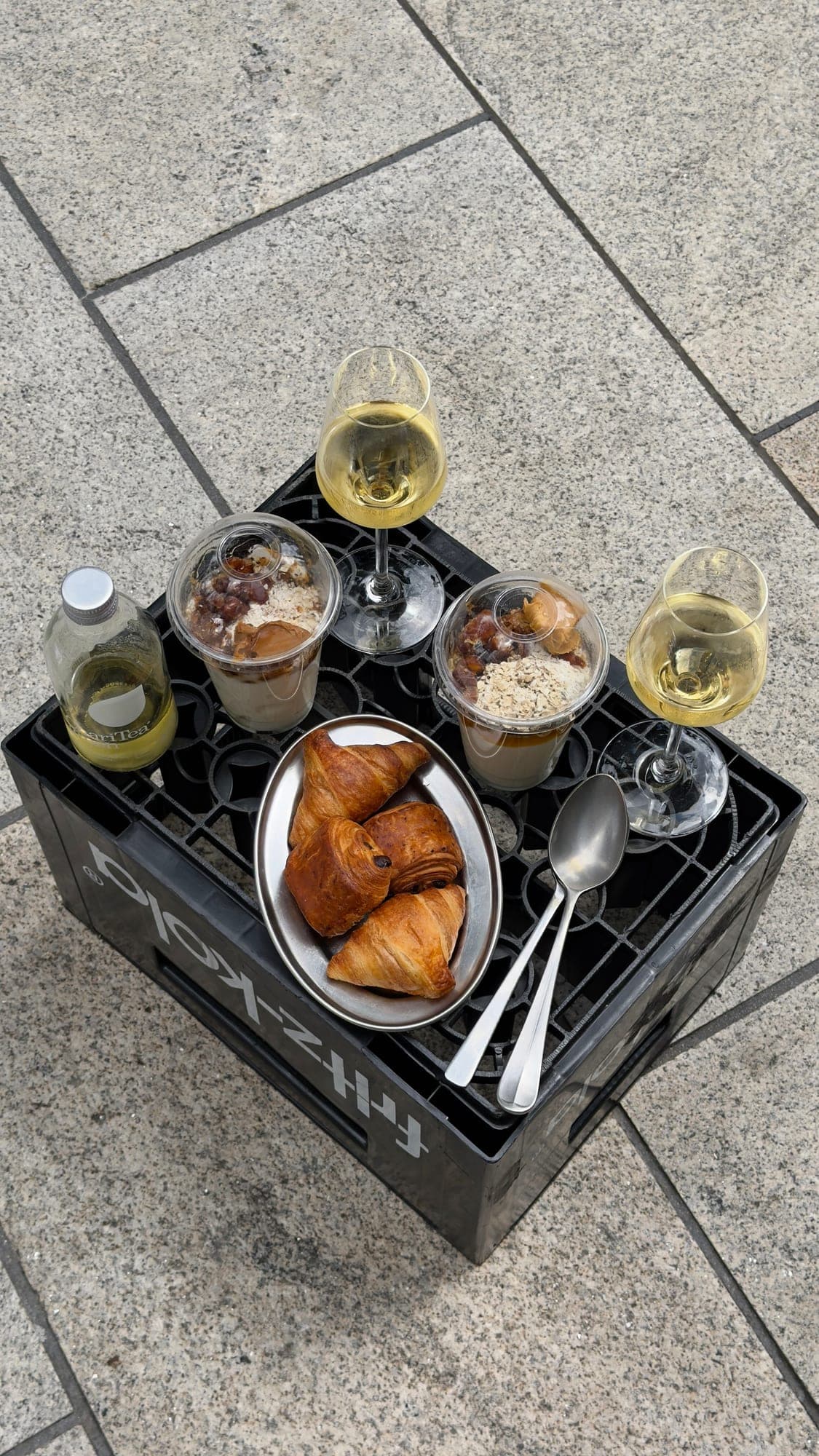 Croissants, Desserts und Weißwein auf einer schwarzen Kiste