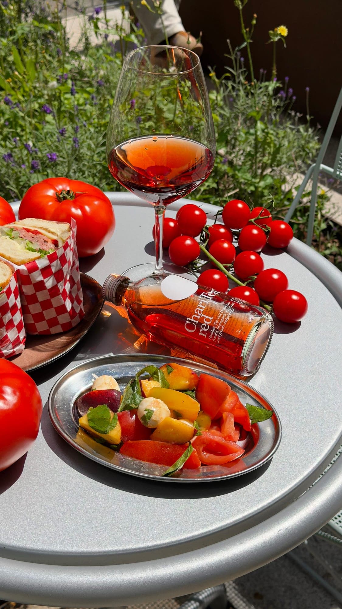 Roséwein, Tomaten, Paprika und ein Sandwich auf einem runden Tisch